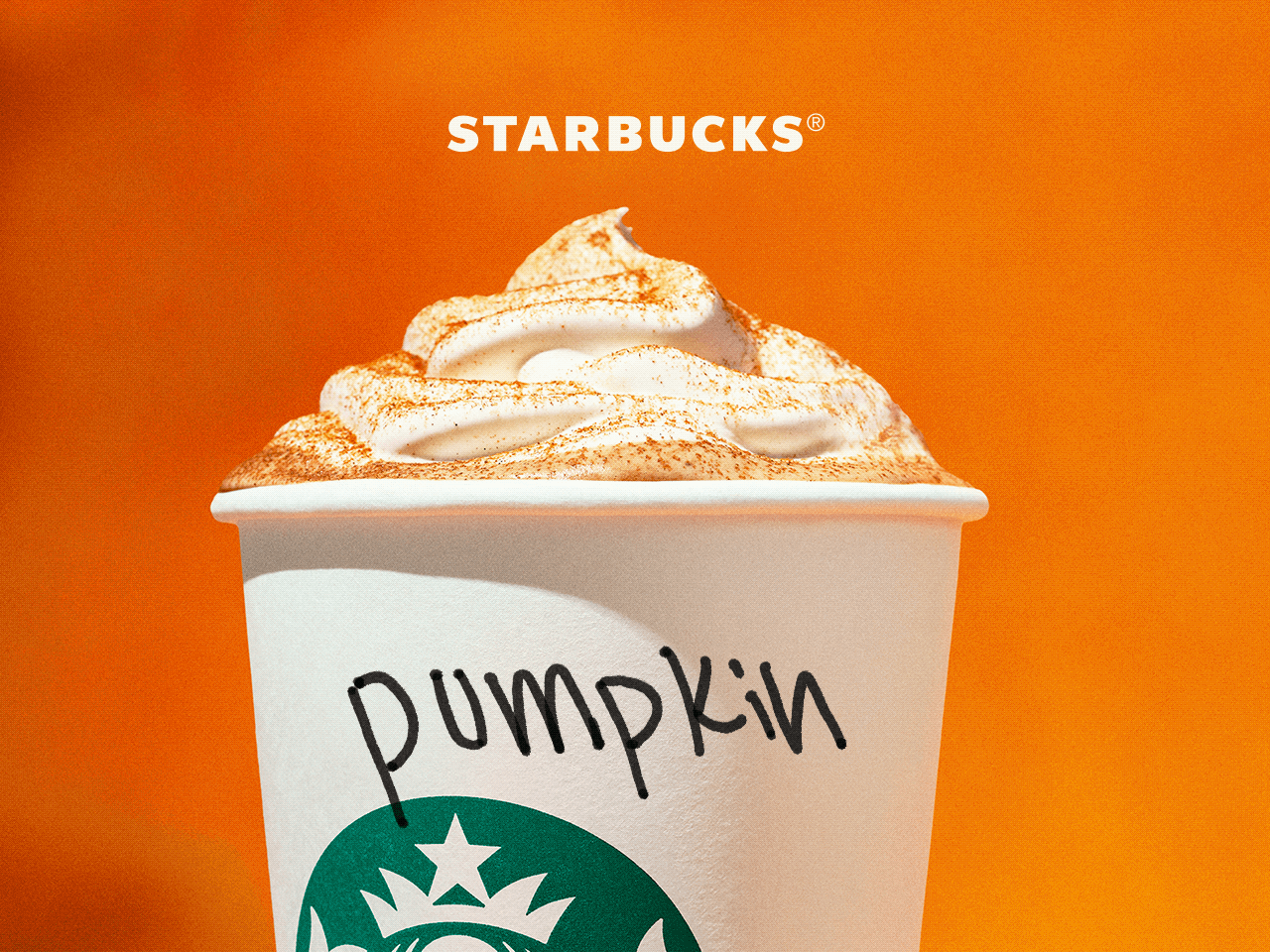 STARBUCKS® | Close-up of to-go cup topped with whipped cream and a sprinkle of spices. On the side of the cup, "Pumpkin" is handwritten in marker.