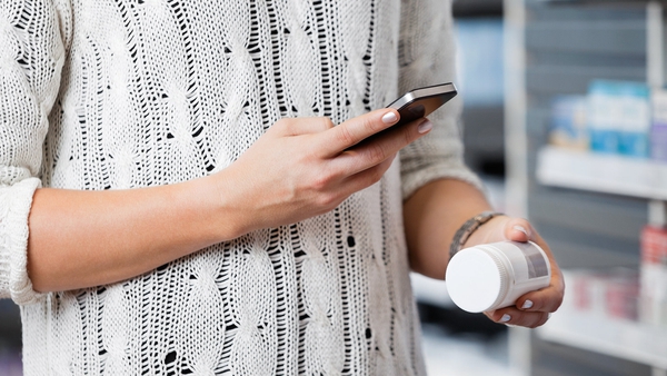 closeup of person holding phone and pill bottle