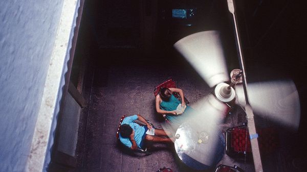 Overhead view of man and woman reading books below a moving ceiling fan.
