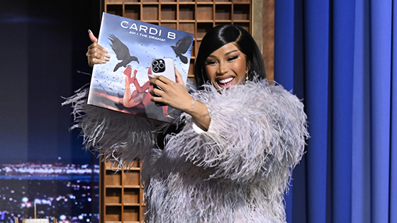 Cardi B holds up an record album.