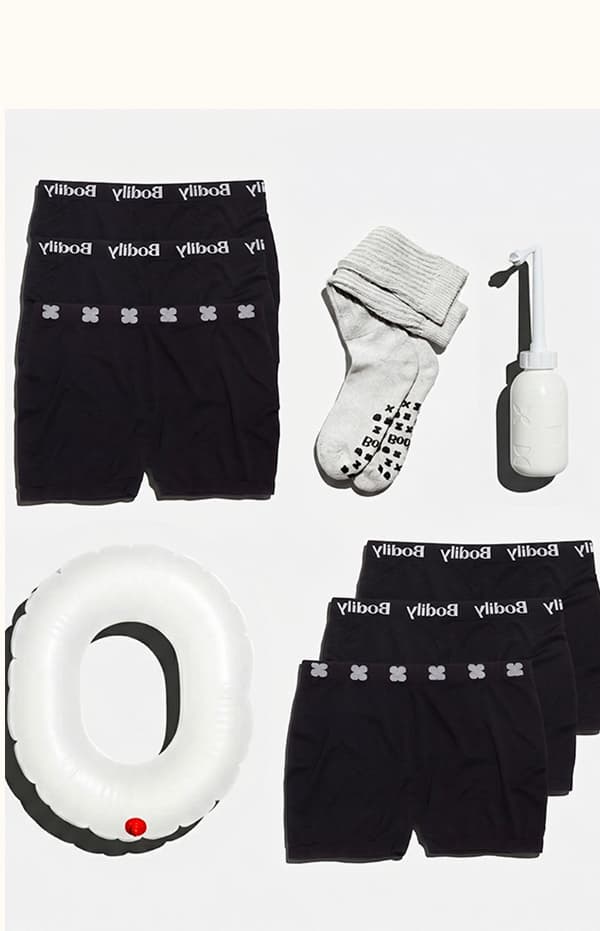 Photo of 6 pairs of black reusable mesh boyshorts, a white blow up donut pillow, a pair of gray socks with grip pads on the bottom, and a white peri wash bottle. 