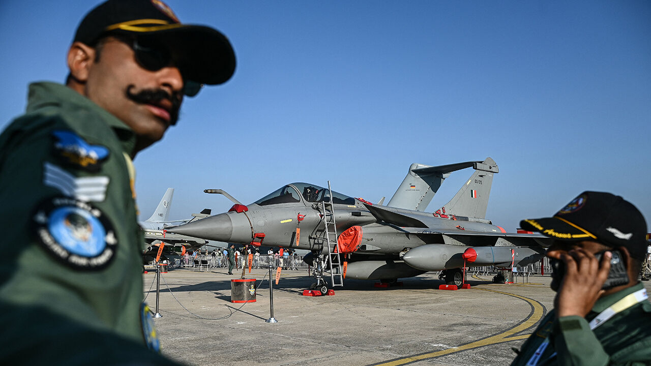 Indian Air Force (IAF) personnel stand in front of the Rafale fighter jet during Aero India