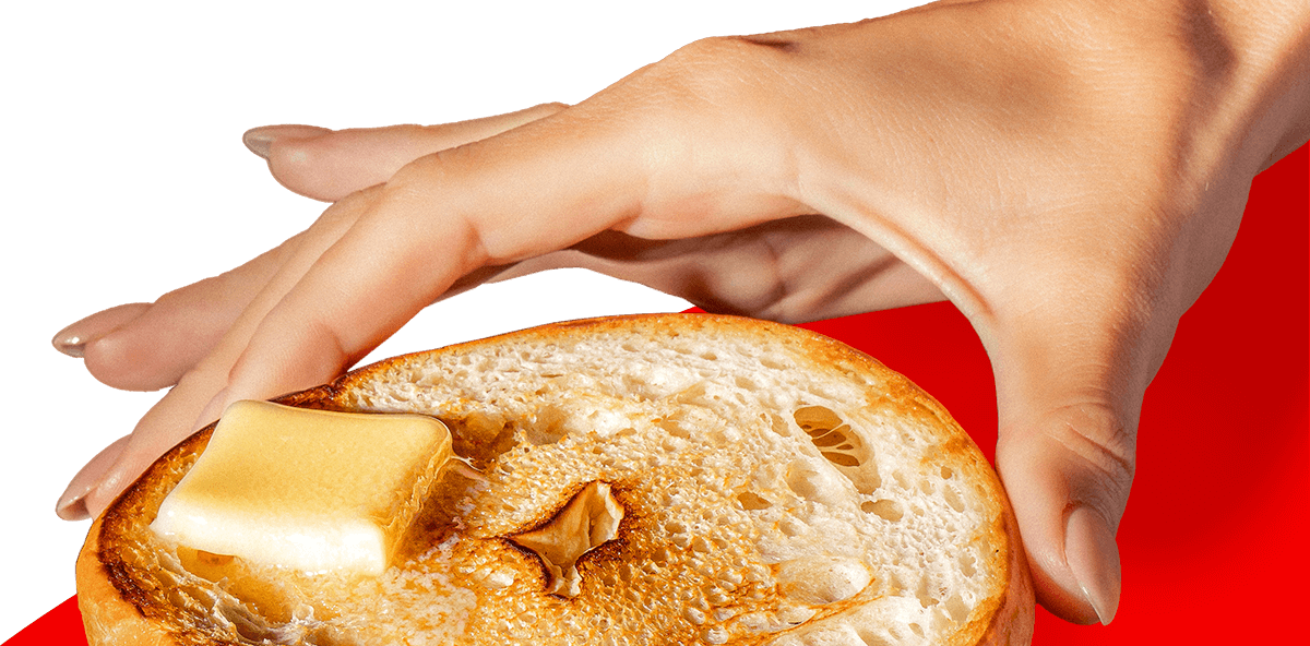 HAND HOLDING A BETTER BAGEL WITH BUTTER ON TO