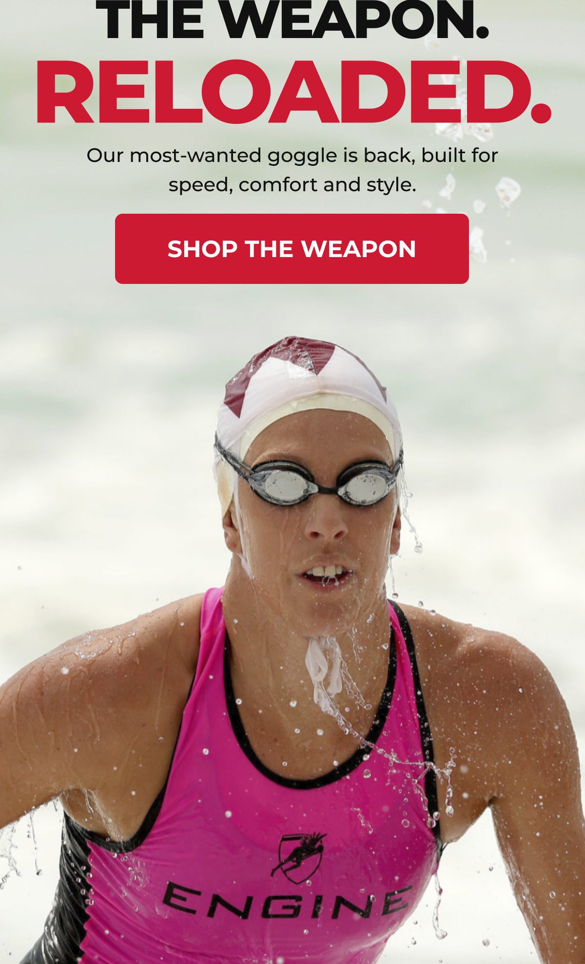 A swimmer wearing goggles and a pink swimsuit, water splashing around her.