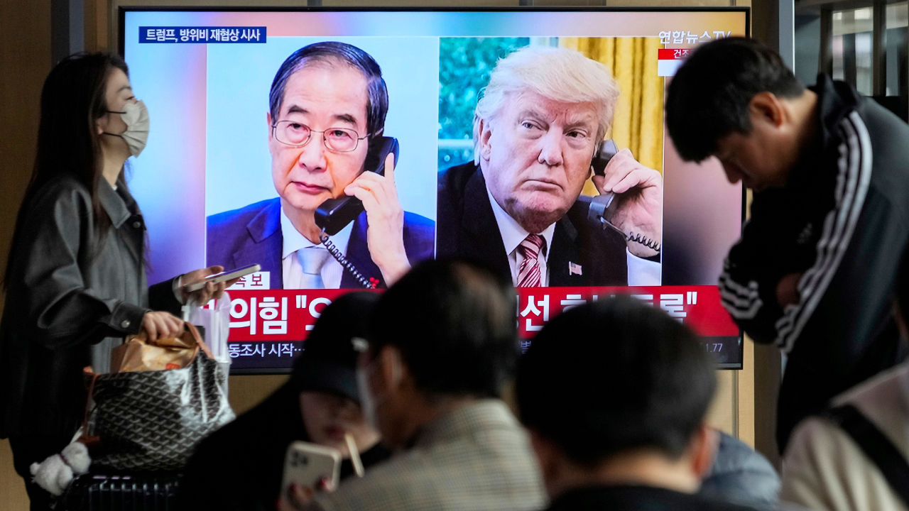 People watch a TV screen showing images of South Korea’s acting president, Han Duck-soo, and America’s president, Donald Trump