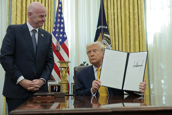 US President Donald Trump holds up an executive order alongside President of Fédération Internationale de Football Association (FIFA) Gianni Infantino in the Oval Office at the White House in Washington, DC, March 7, 2025. © 2025 Anna Moneymaker/Getty Images