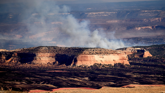 Smoke billows behind a rock formation.