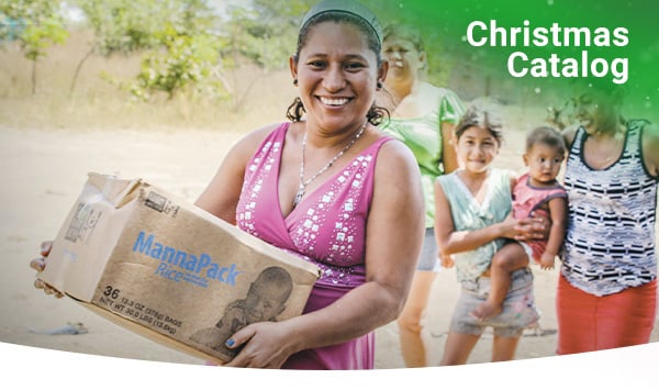 A woman holds a brown box of food and smiles.