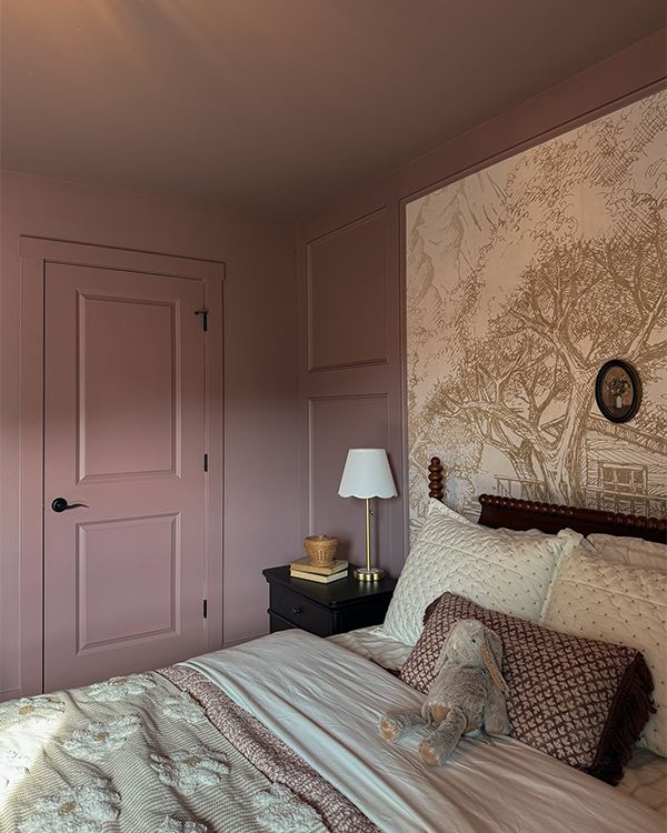 A purple-painted bedroom with a bed, night stand, and large artwork above the headrest.