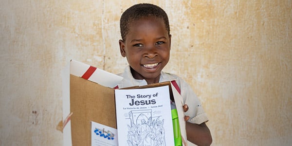 A young student holds a Box of Joy with The Story of Jesus inside.