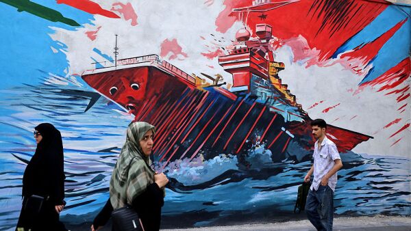 Commuters walk past a wall mural along the street in Tehran on July 21, 2026.