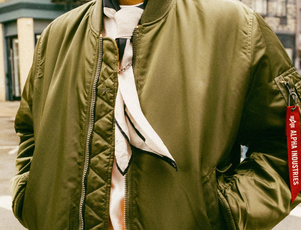 An image of a person's torso in an olive green alpha industries jacket