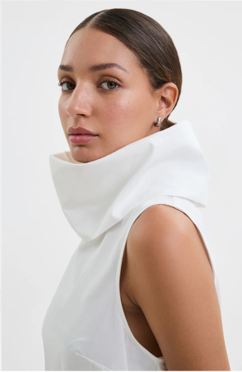 Carmel wearing the Marcy Sleeveless Top with a dramatic collar looks to the side with a calm expression.