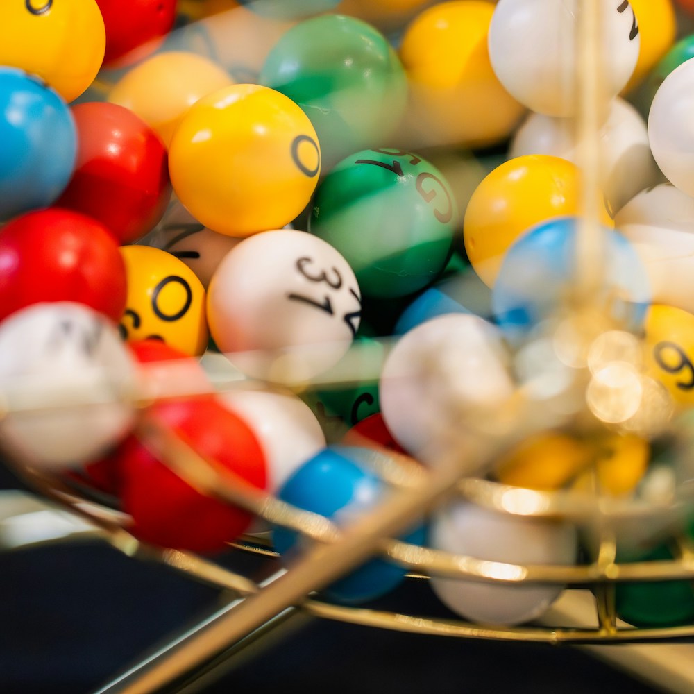 A close-up on colorful bingo balls tumbling around in their metal cage. 