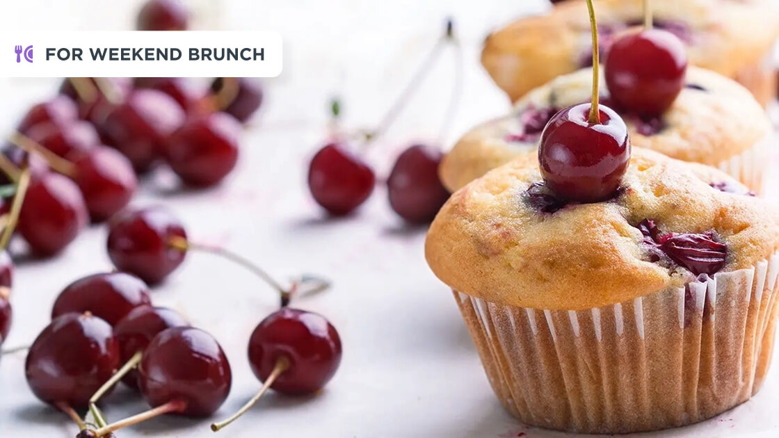Several loose cherries and a cherry muffin to the right. 