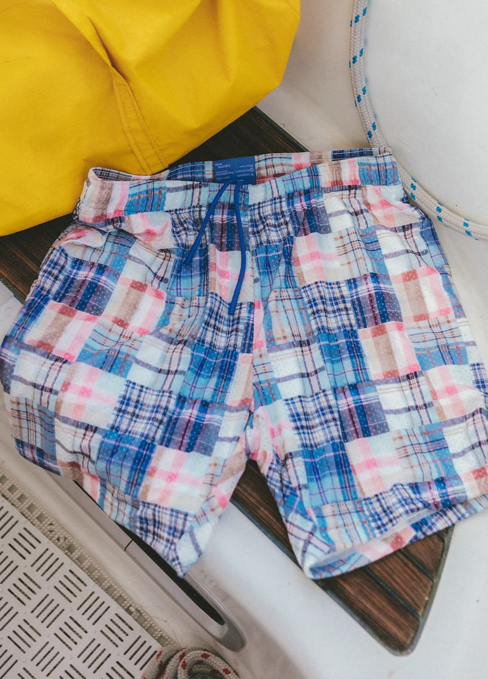 Pair of blue madras lounge shorts laid on a seat of a boat.