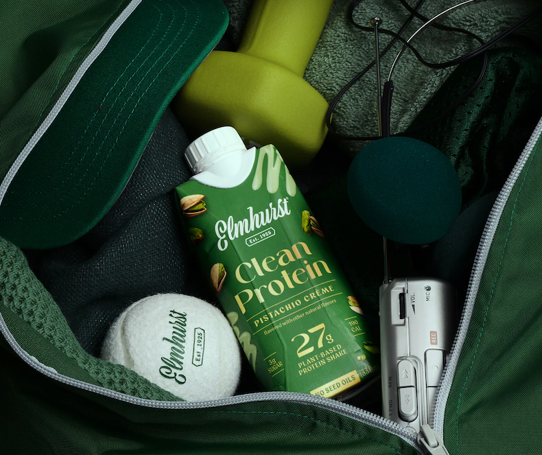 Clean protein in a gym bag with a tennis ball, camera, and weight | Shop Clean Protein