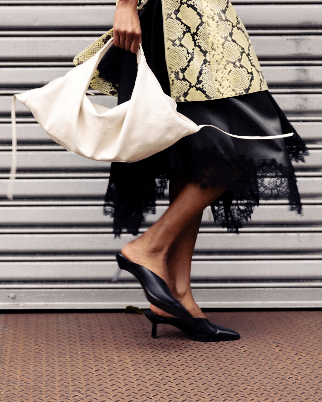 an image of a woman in a black dress and heels carrying a white bag