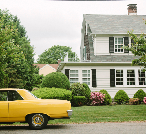 Classic car outside of a colonial style home