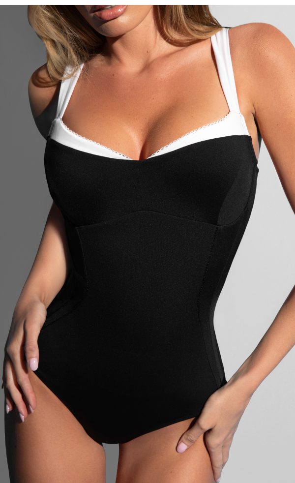 A woman wearing a black and white one-piece swimsuit, posing confidently.