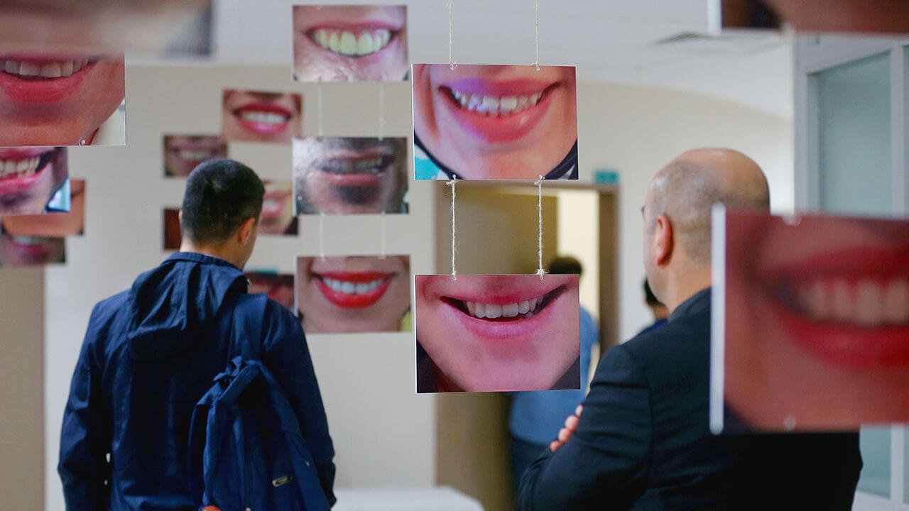 People look at the photos of smiling teeth at a dentist's exhibition. 