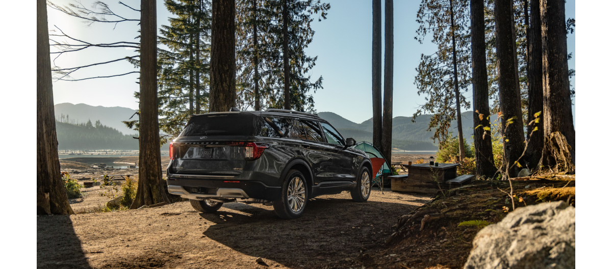 A Ford Explorer® SUV parked at a remote campsite with trees and a lake visible in the background
