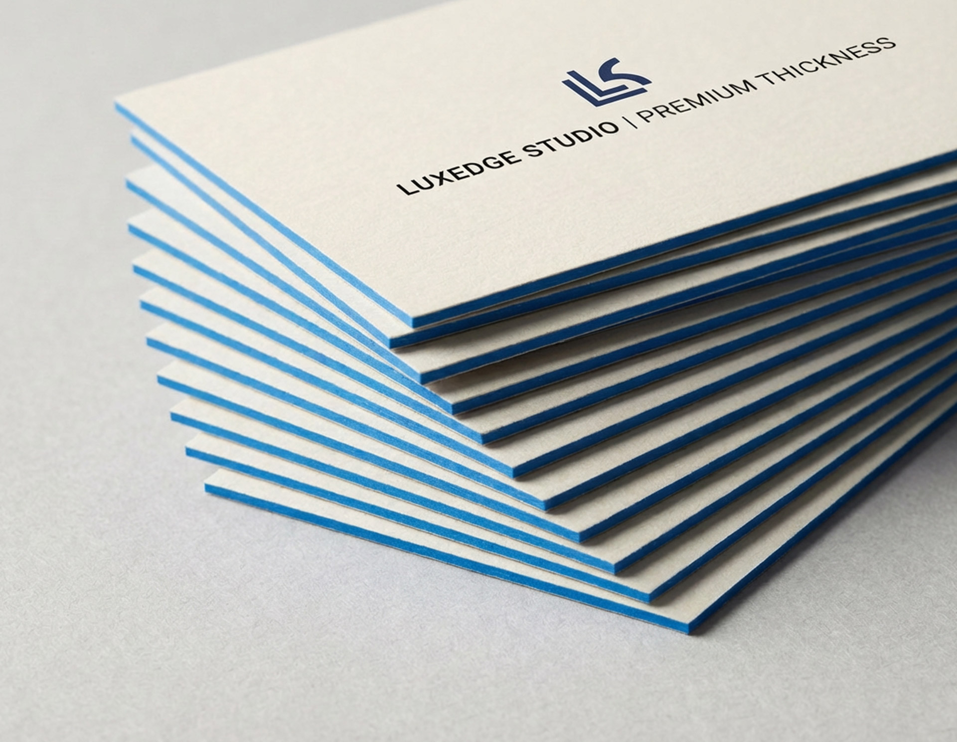 Stack of premium thick business cards with white faces and bold blue color edges.