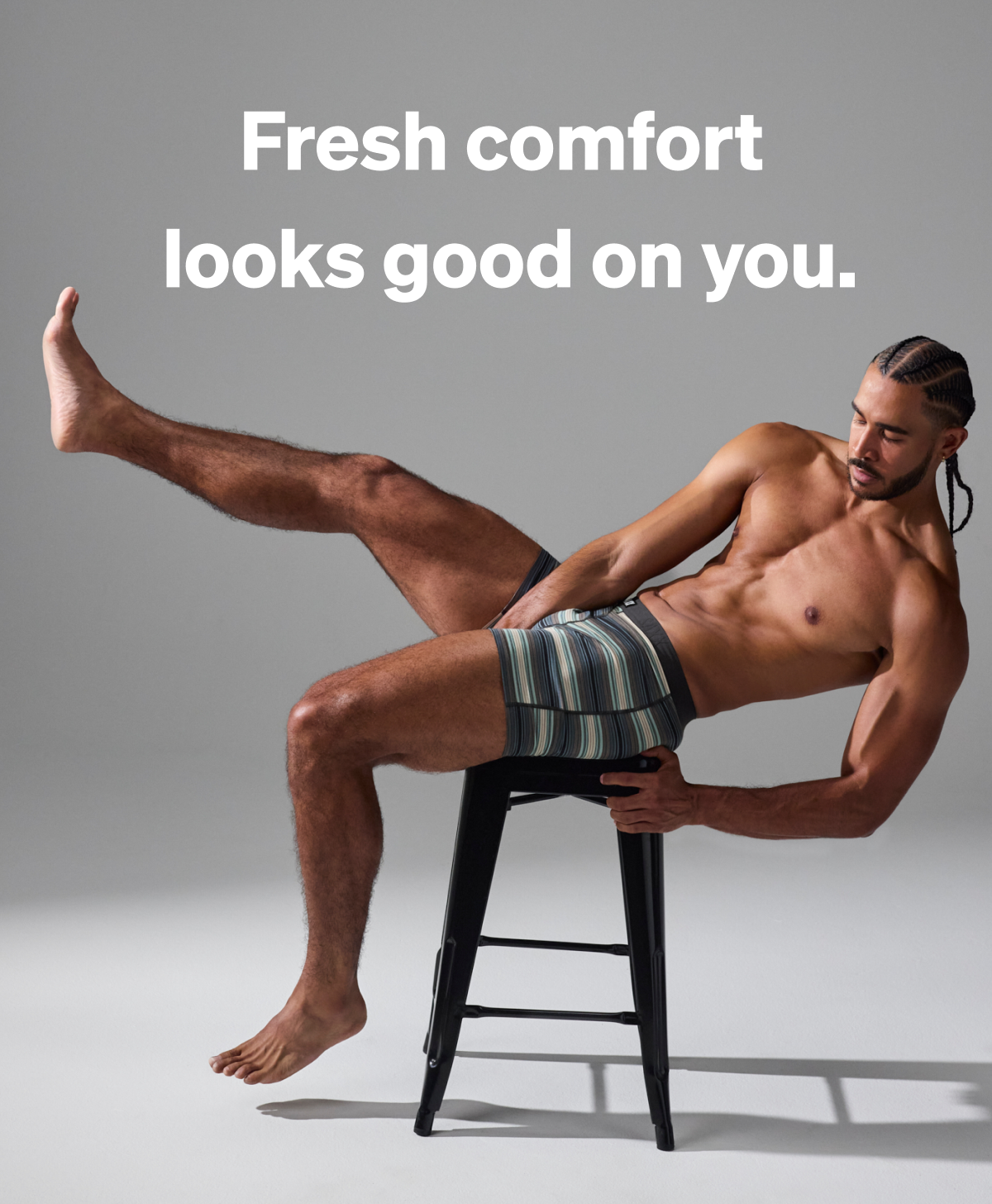 Model reclining on a stool wearing striped boxer briefs with the headline “Fresh comfort looks good on you,” showcasing a modern fit and everyday comfort.