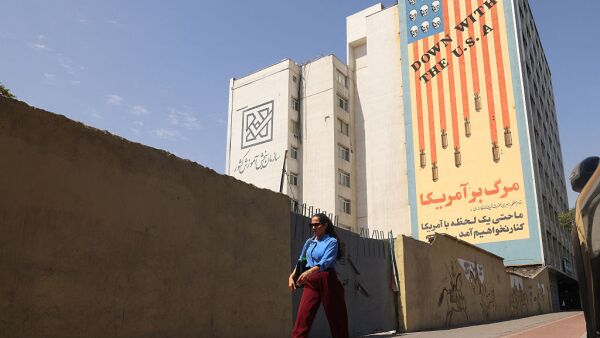 An Iranian woman walks past an anti-US banner in Tehran on July 19, 2026.