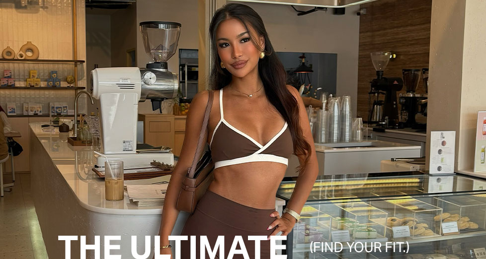 Fashionable woman in brown activewear sports bra & leggings, posing in a stylish cafe. Find your ultimate fit and comfort.