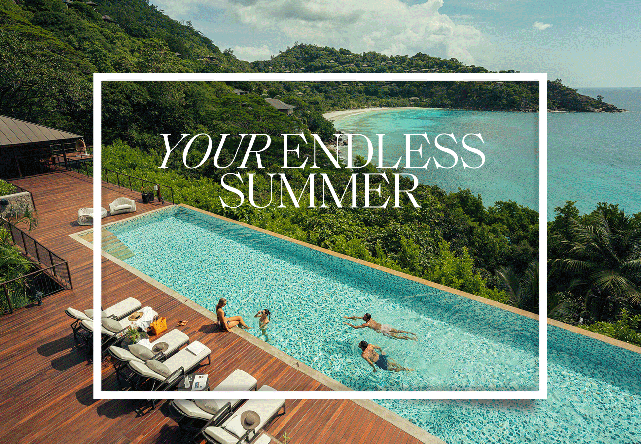 Hero GIF featuring 5 frames with white text overlay that reads 'YOUR ENDLESS SUMMER': 1) Infinity pool overlooking tropical coastline with guests swimming and lounging on a wooden deck. 2) A woman views elephants in a grassy savannah walking around a watering hole. 3) Two men and a child play paddleball in shallow ocean water. 4) A couple drive along a palm-lined boulevard in a vintage convertible. 5) A group of people at dinner raise glasses in a toast near a rocky coastline at sunset.
