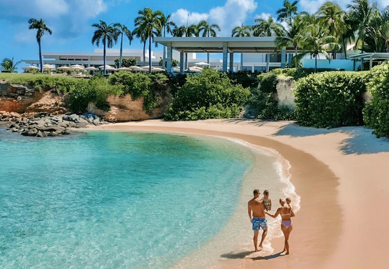 A family walking along a sandy beach with the resort in the background.