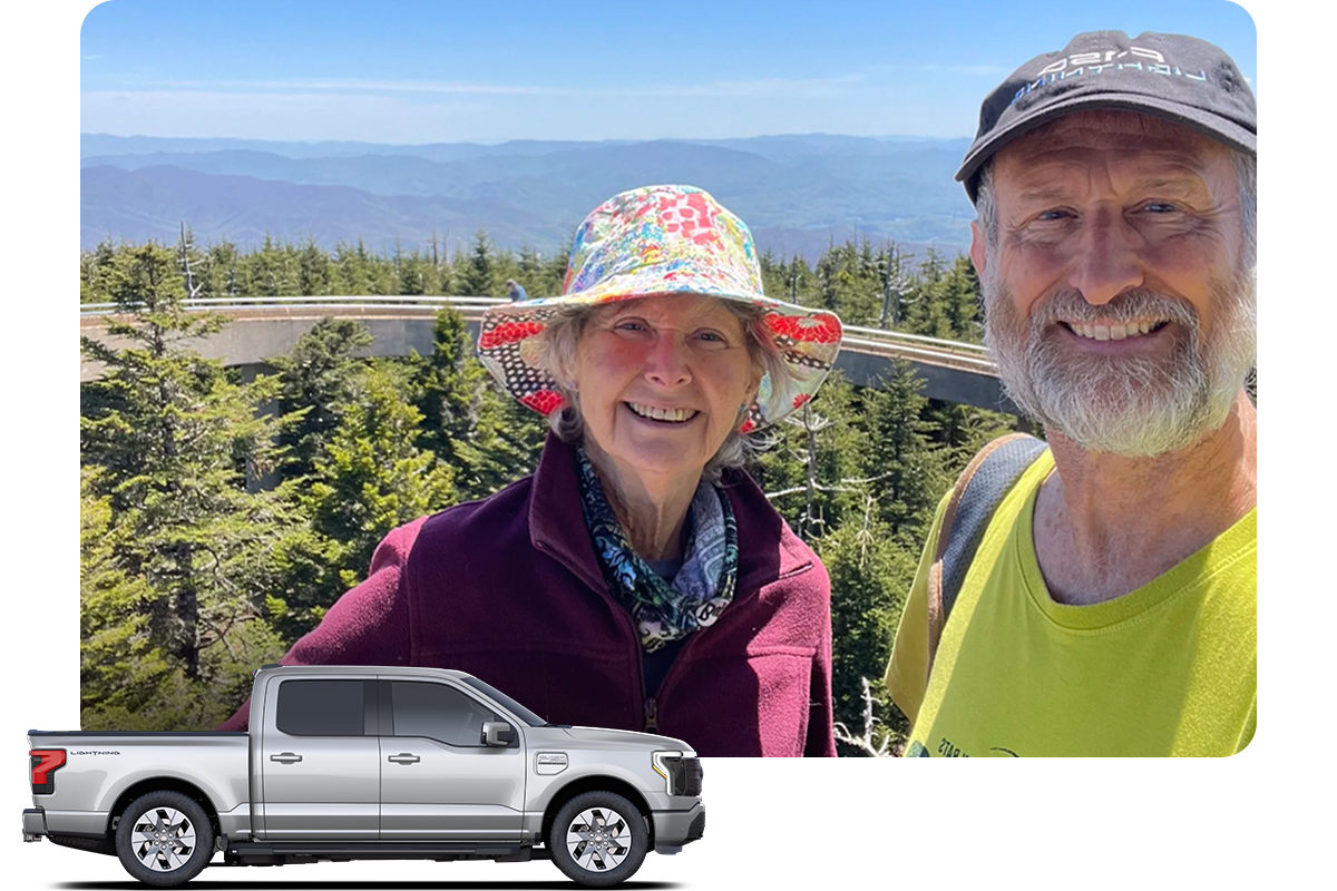 A man and a woman smiling in a forested landscape, with a Ford F‑150&reg; Lightning&reg; truck placed in front of the image