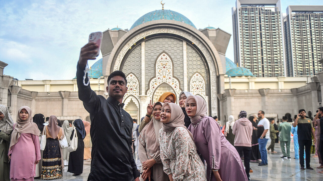People take a selfie with the backdrop of the Federal Territory mosque in Kuala Lumpur.