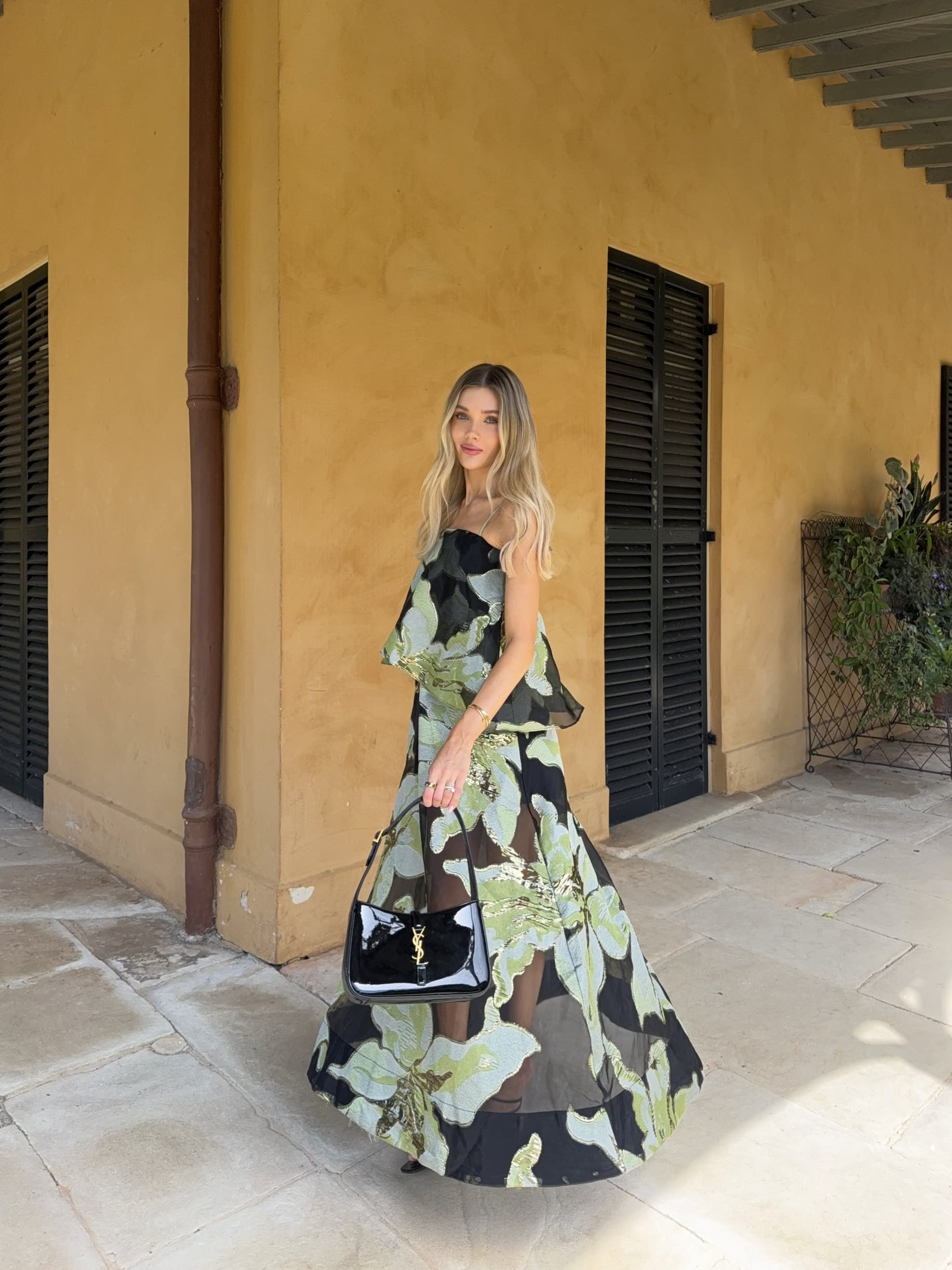 an image of a woman in a dress standing by a pillar