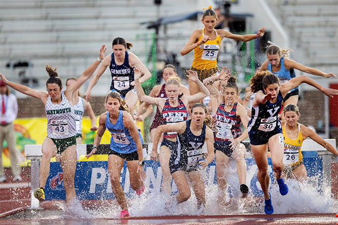 Runners splash through a puddle of water at the Penn Relays.