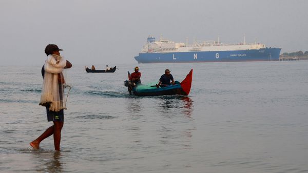 Fishermen in their traditional boats pass through the Arabian Sea with the LNG tanker Al Reef in the background in Kochi, India.