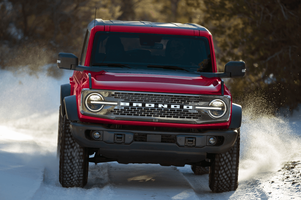 A Ford Bronco&reg; SUV being driven across snow while its wheels kick up snow behind it.