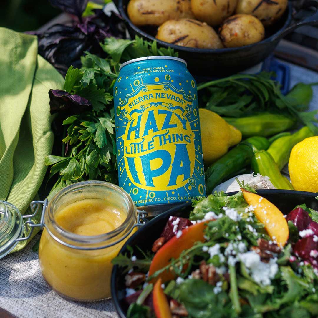 A can of Hazy Little Thing next to a salad and a jar of vinaigrette