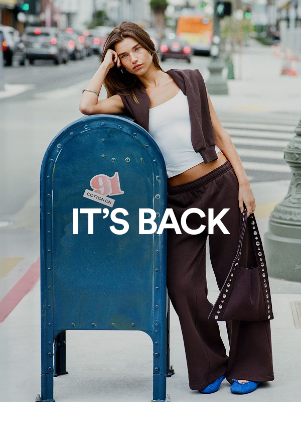 Woman posing next to blue mailbox with "IT'S BACK" text