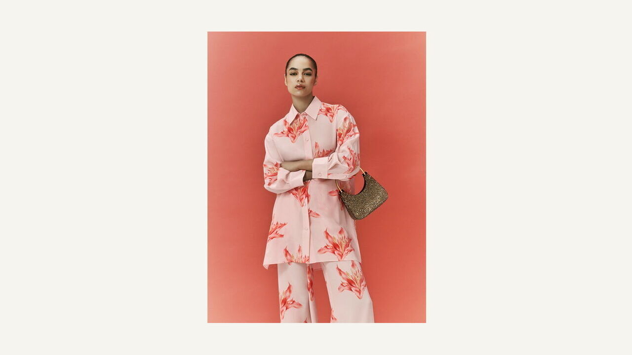 Model wearing Alexander Mcqueen exclusive ramadan collection floral suit, holding a handbag.