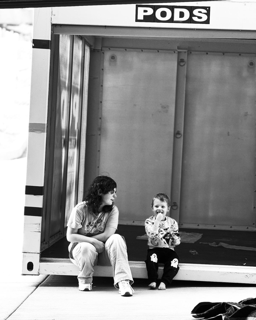 Two fair-skinned children sitting in an empty moving van