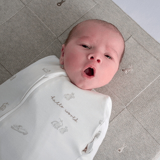 Baby yawning in bunny style swaddle, lay on bunny embroidered blanket