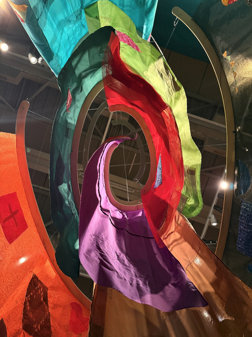Looking up at coloured material hung in a spiral pattern.
