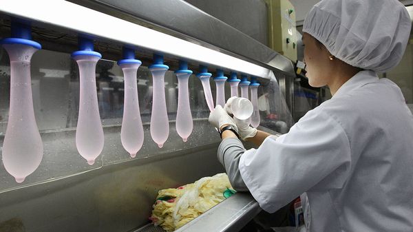An employee inspects condoms during testing in the research laboratory at the Karex Industries condom factory in Pontian Besar, Malaysia