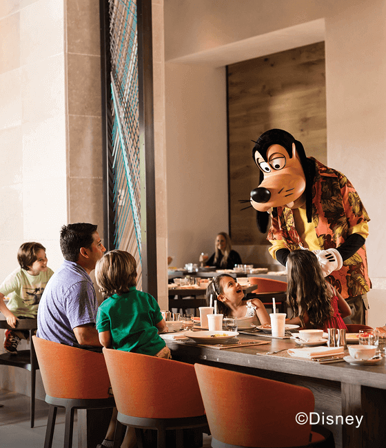 Goofy greeting a family dining in a restaurant.