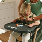 Toddler in highchair, Mum is buckling him in.