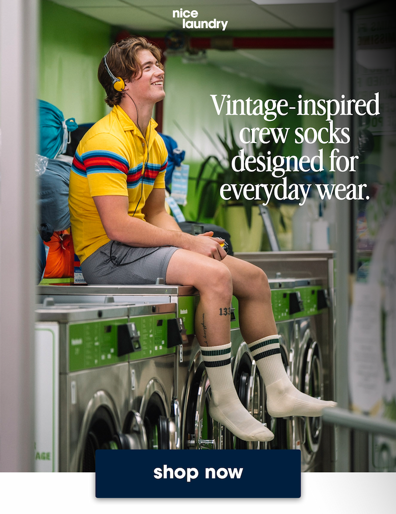 Vintage-inspired  crew socks  designed for  everyday wear. Man sitting on laundry machine wearing grey shorts,yellow polo and tech varsity crew socks