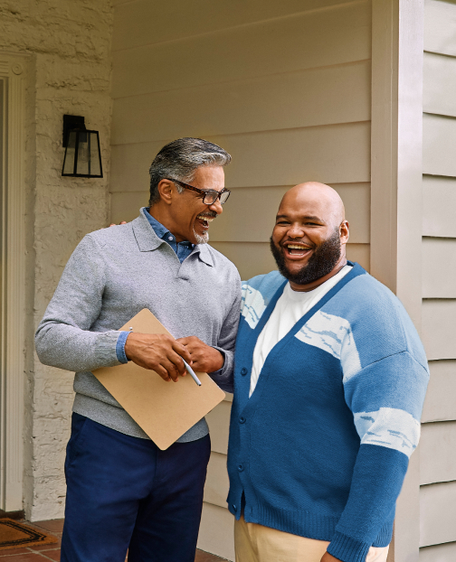 Real estate agent and potential buyer talking on a front porch.