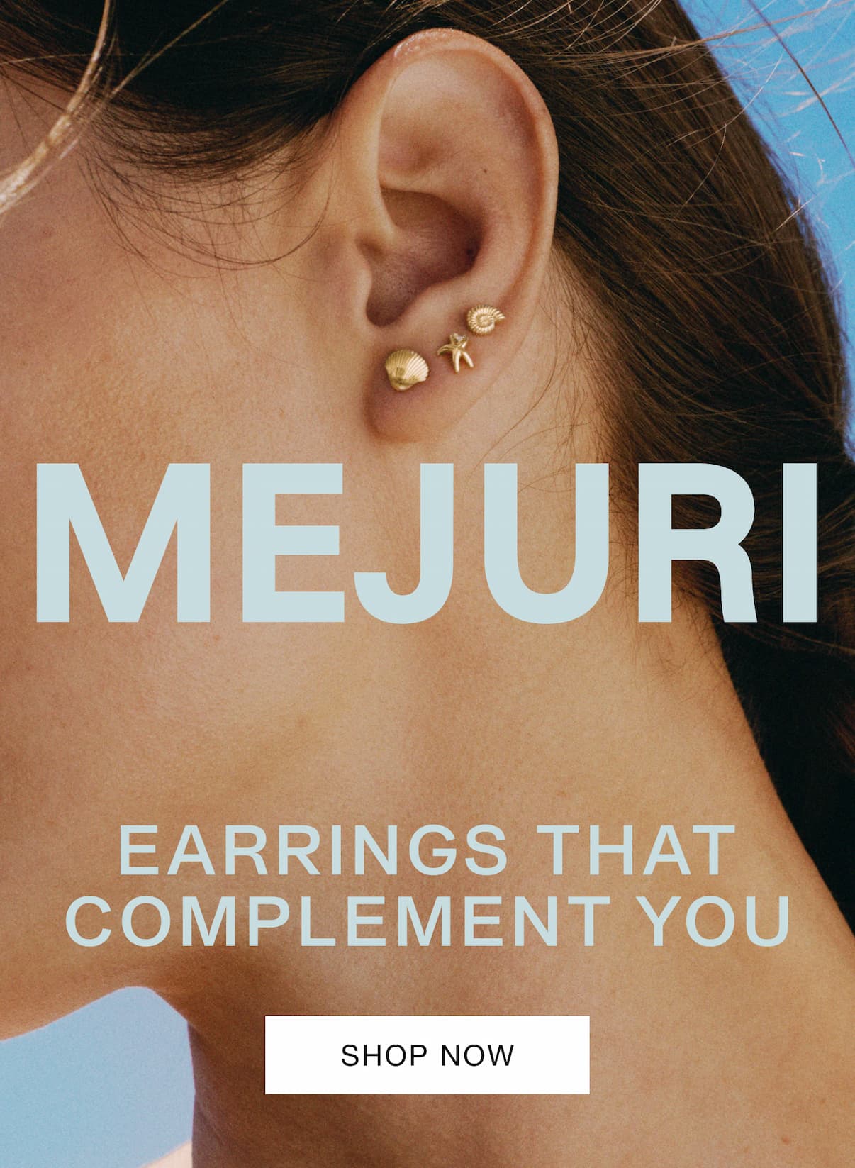 Close-up of a woman's ear wearing small Mejuri gold studs against a bright blue sky — Mejuri, Earrings That Complement You.